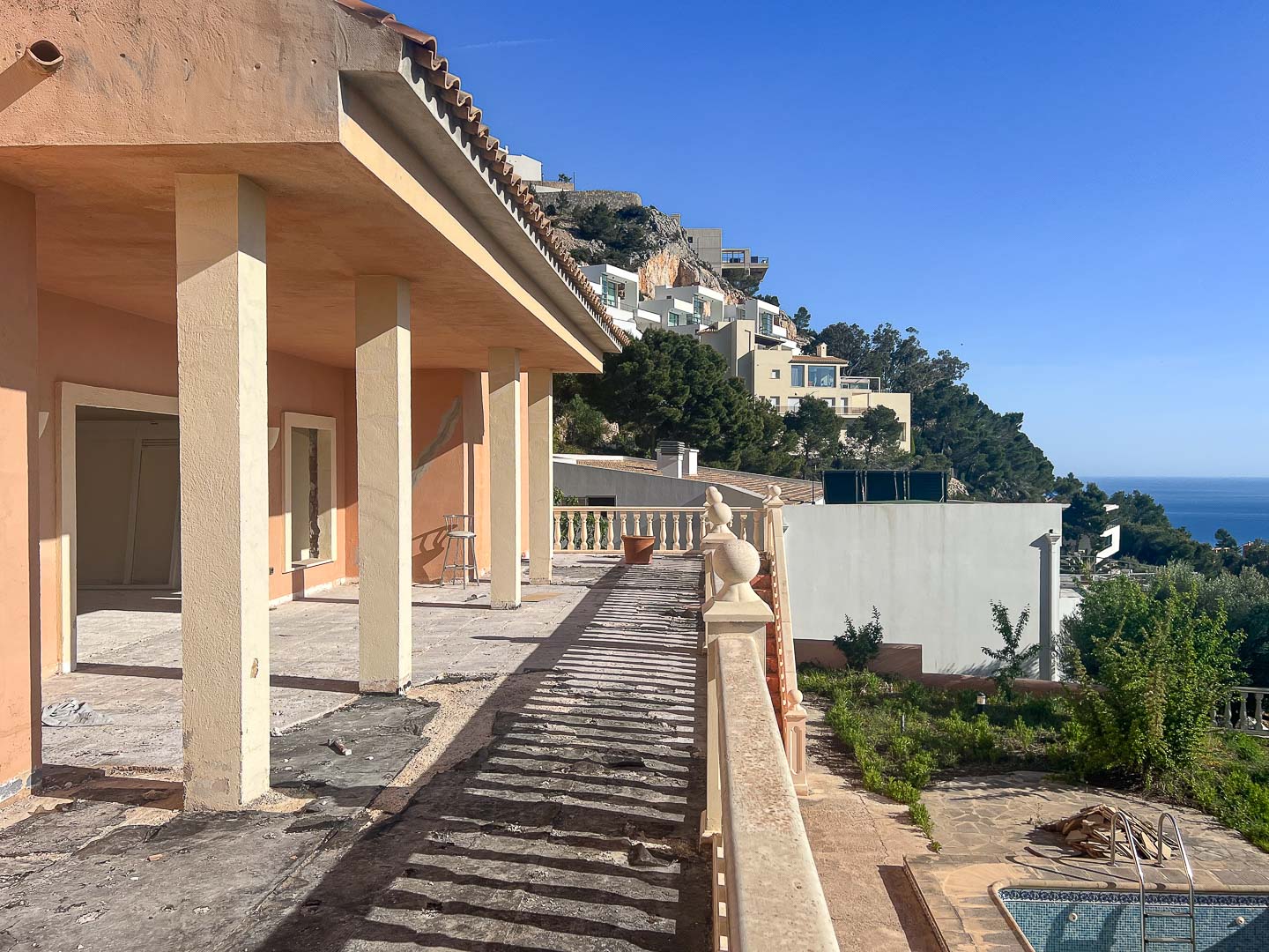 Buitenterras in renovatie met structurele kolommen, een klassieke balustrade en panoramisch uitzicht over de heuvels van Altea en de Middellandse Zee.