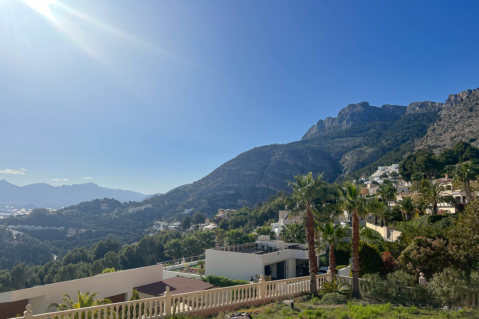 Panoramisch uitzicht vanuit Altea Hills op het Sierra de Bernia-gebergte, witte villa's tegen de heuvels en weelderige mediterrane beplanting.
