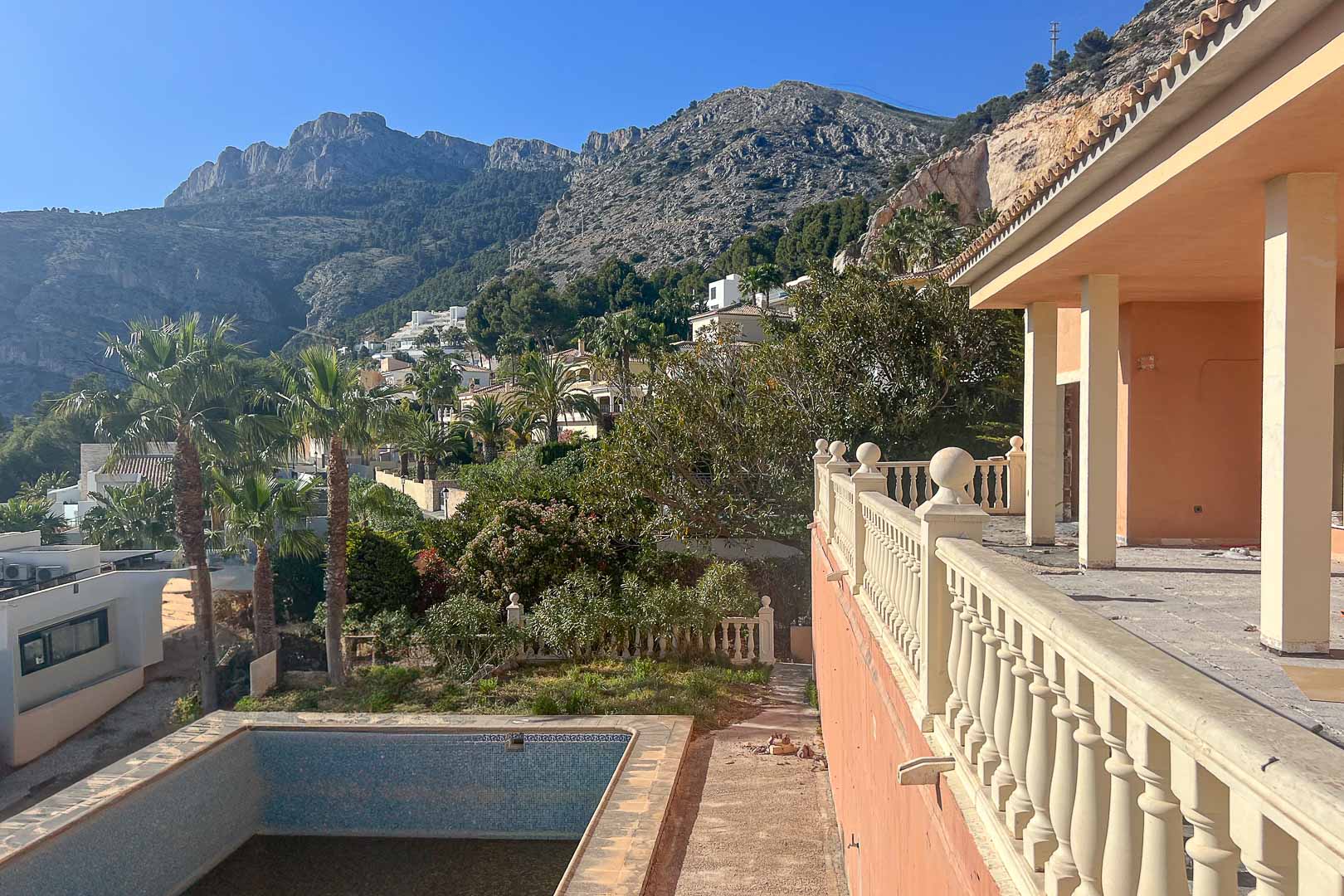 Terras met klassieke balustrade en uitzicht op de Sierra de Bernia. De buitenruimte omvat een privézwembad en volgroeide mediterrane beplanting.