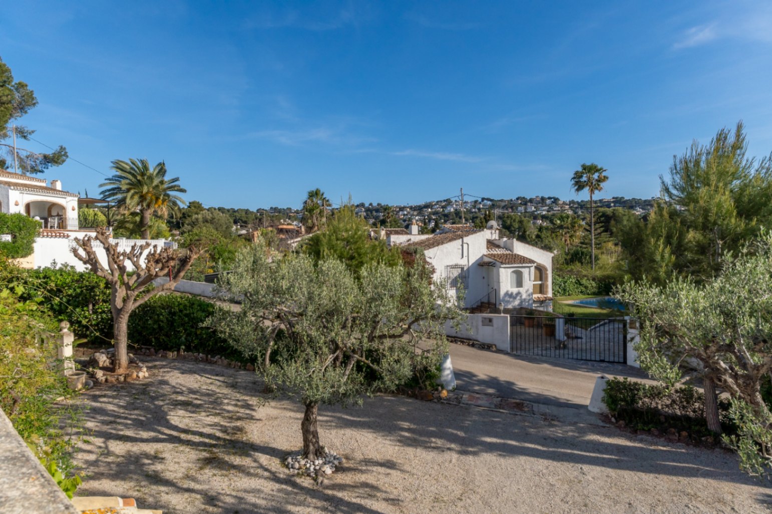 Buitenaanzicht van de villa met een mediterrane tuin, olijfboom en vrij uitzicht over de omliggende heuvels van Jávea.