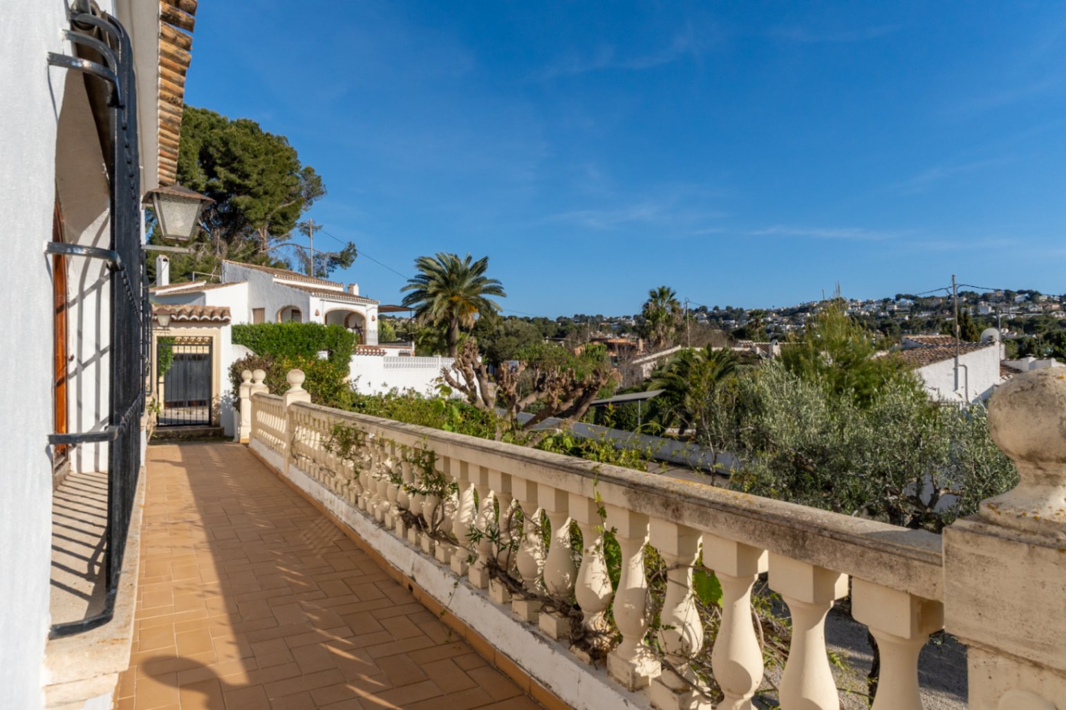 Buitenterras met traditionele terracotta tegels en een klassieke balustrade met uitzicht over de woonwijk Cap Martí in Jávea.