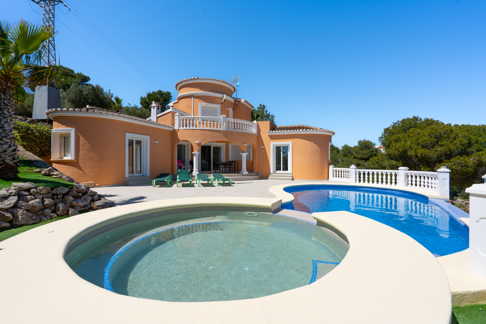 Exterieur van de villa met een niervormig zwembad inclusief rond ondiep gedeelte, ruim terras en mediterrane architectuur met terracotta gevels.