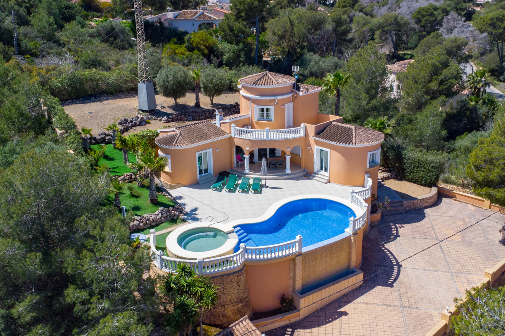 Luchtfoto van de mediterrane villa met niervormig zwembad, geïntegreerde jacuzzi, ruim betegeld terras en traditionele architectuur in Jávea.