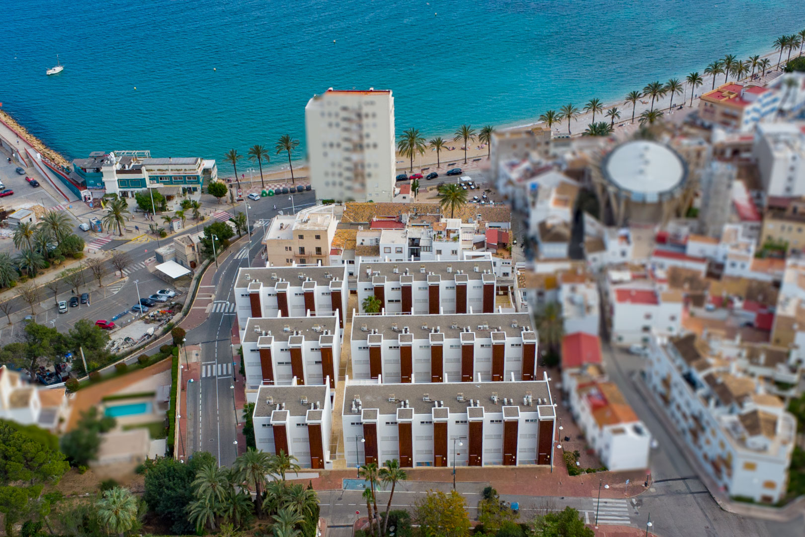 Luchtfoto van het wooncomplex nabij de haven van Jávea, met de moderne architectuur en de directe nabijheid van de Middellandse Zee en de boulevard.