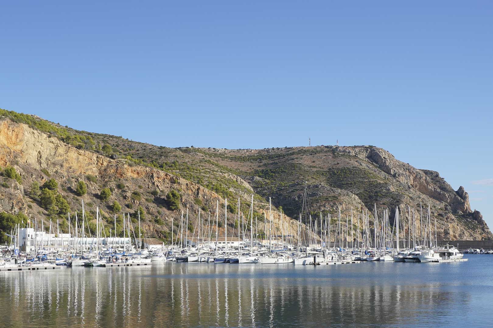 Panoramisch uitzicht op de jachthaven van Jávea met zeilboten en jachten tegen de achtergrond van Cabo de San Antonio, gelegen op korte afstand van de woning.