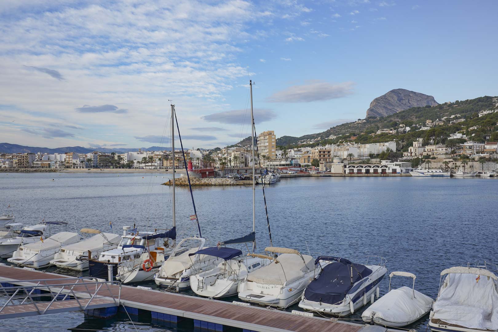 Panoramisch uitzicht over de jachthaven van Jávea met afgemeerde boten en het indrukwekkende Montgó-massief aan de horizon.