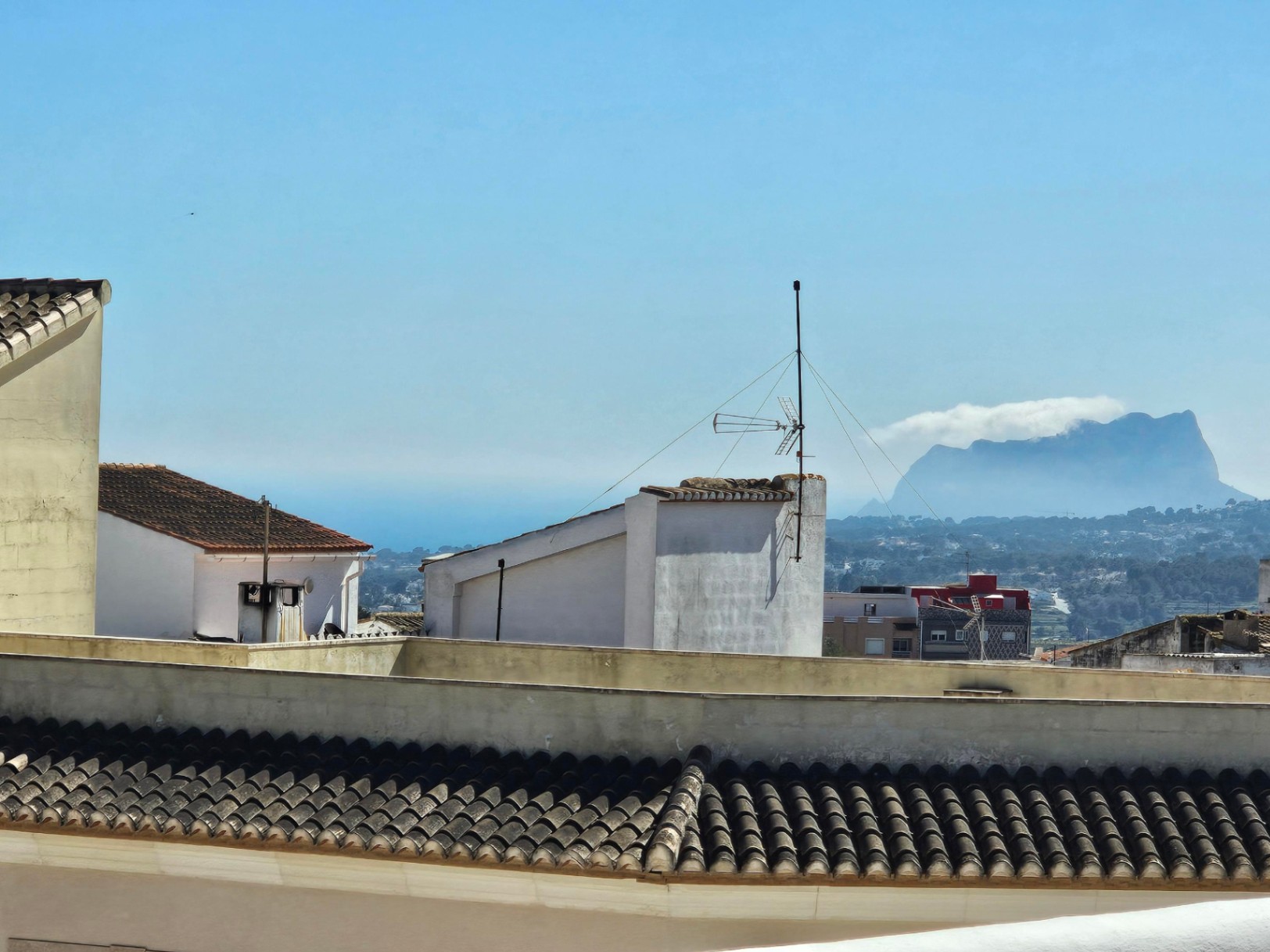 Panoramisch uitzicht vanaf het bovenste terras over de daken van het dorp, de Middellandse Zee en het silhouet van de Peñón de Ifach.