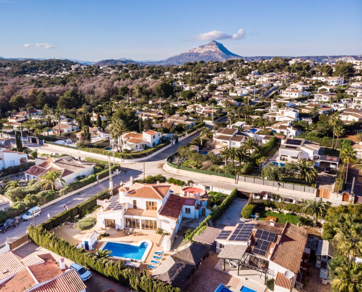 Luchtfoto van de villa in Costa Nova Pla met het privézwembad, zonnepanelen op het dak en de berg Montgó op de achtergrond.
