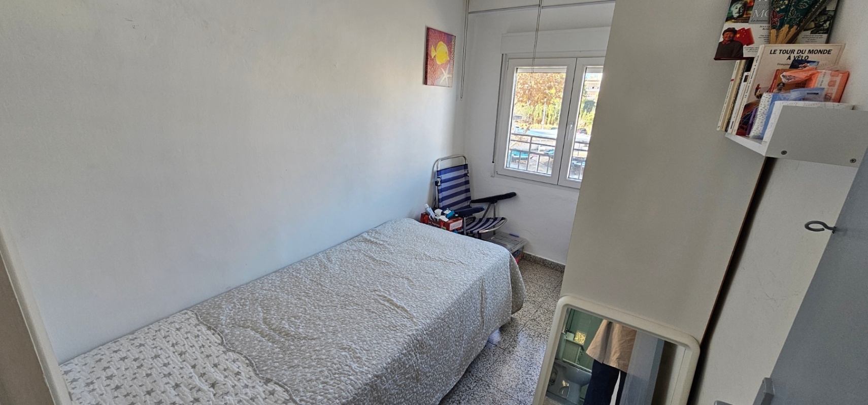 Eenpersoonskamer met een traditionele terrazzovloer, een bed met sterrenpatroon en een raam dat zorgt voor natuurlijk daglicht.