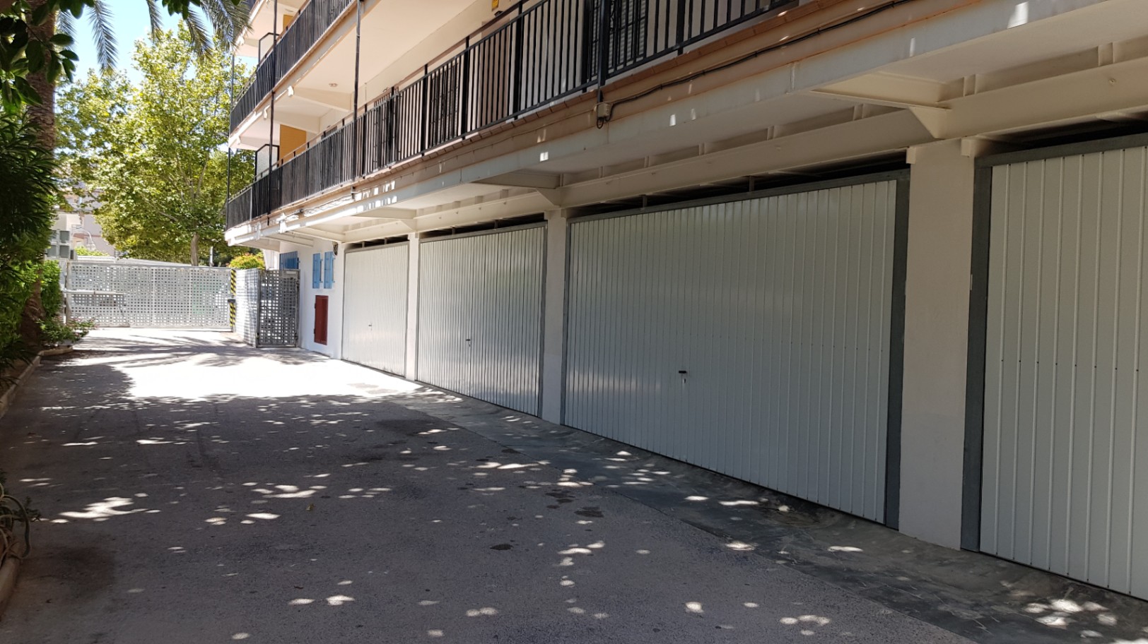 Privé garageboxen met witte metalen deuren, gelegen op de begane grond van het gebouw met directe toegang vanaf de geasfalteerde gemeenschappelijke oprit.