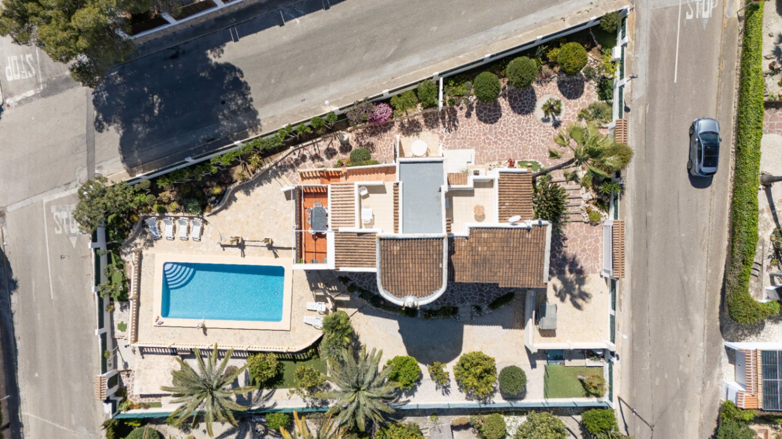 Bovenaanzicht van het perceel van 1030 m² met het privézwembad, de aangelegde mediterrane tuin met palmbomen en de verschillende terrassen van de villa.