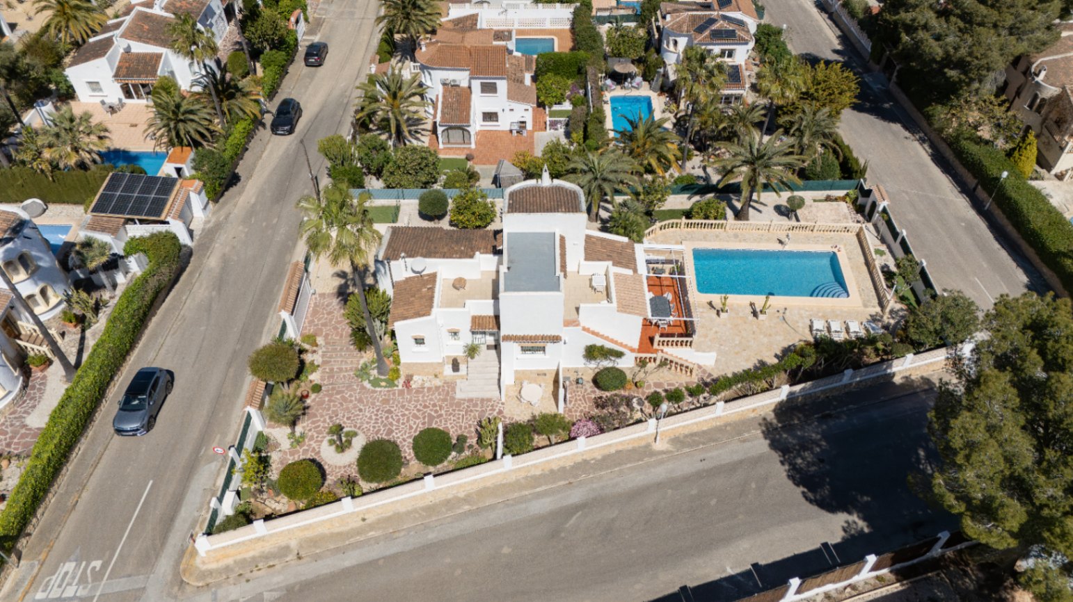 Luchtfoto van de villa op een hoekperceel met privézwembad, ruime geplaveide terrassen en een verzorgde mediterrane tuin in de wijk Pinosol.