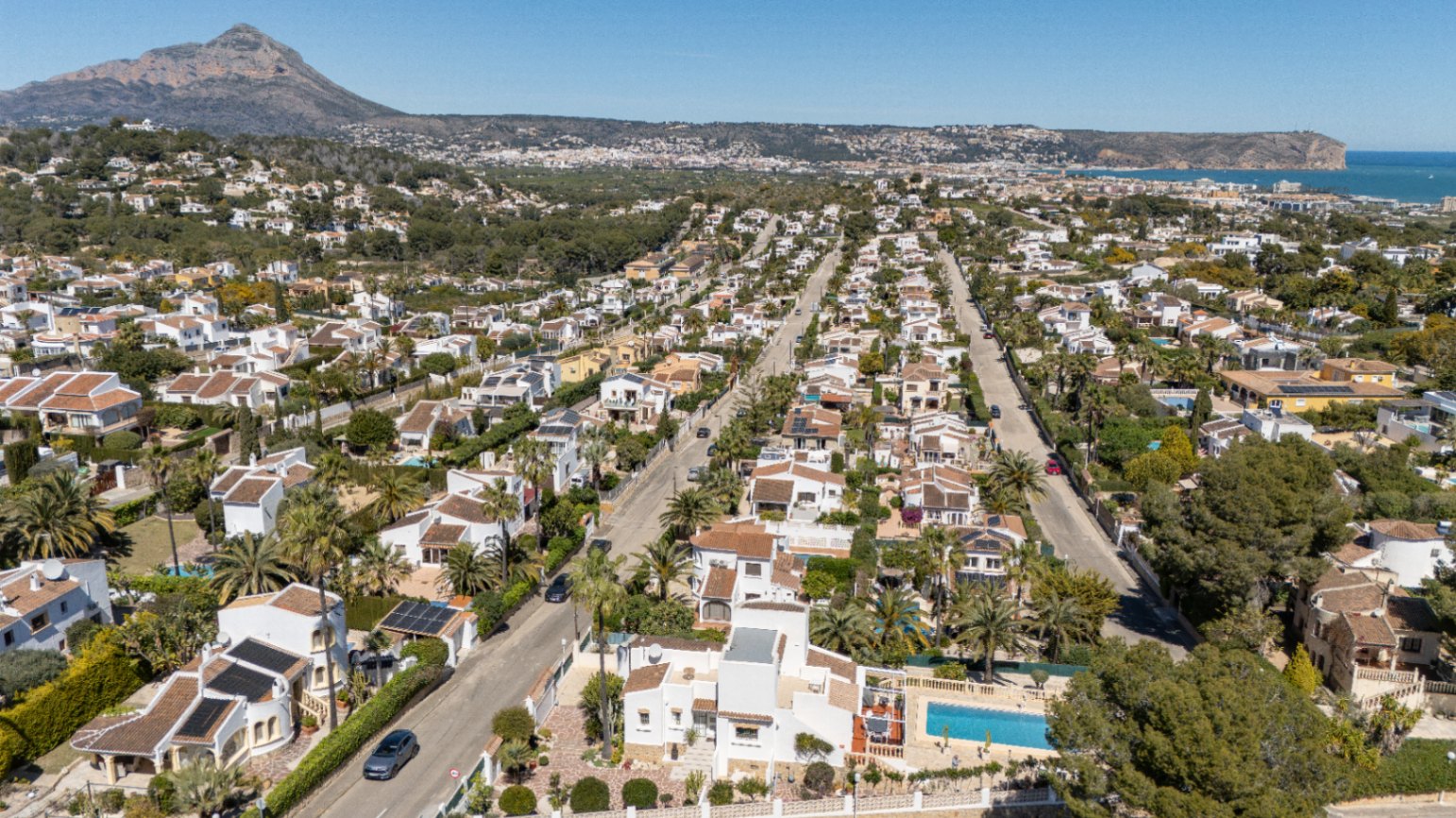 Luchtfoto van de woonwijk Pinosol in Jávea, met zicht op de Middellandse Zee en het panoramische uitzicht op de iconische Montgó-berg.