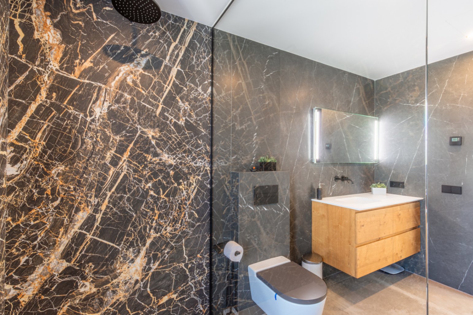 Moderne badkamer met inloop-regendouche, donkere marmerlook tegels, een zwevend houten wastafelmeubel en een verlichte spiegel.