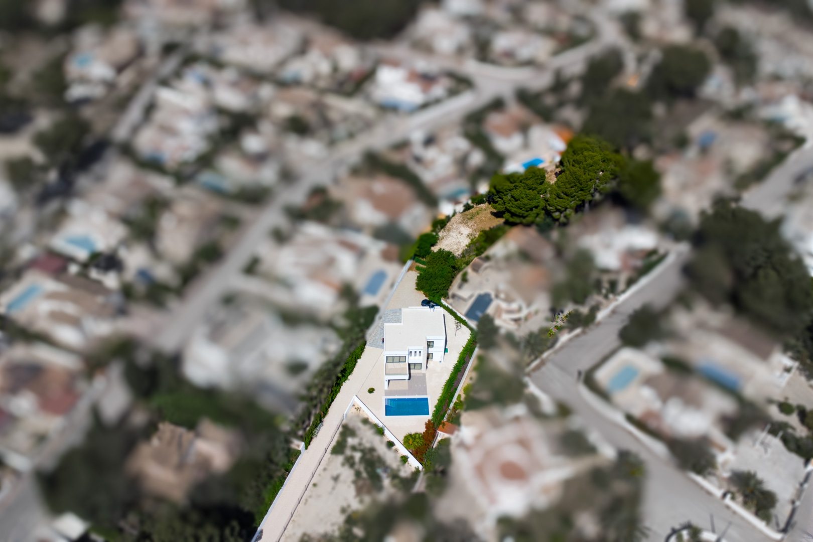 Luchtfoto van de moderne villa op een royaal vlak perceel, met het rechthoekige zwembad en de grote extra tuinzone duidelijk zichtbaar in La Fustera.