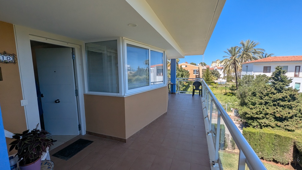 Entreeterras met terracotta-stijl tegels en glazen balustrades, met uitzicht op het gemeenschappelijke groen en de omliggende mediterrane villa's in Jávea.