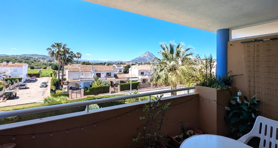 Privéterras met metalen reling en vrij uitzicht op de Montgó-berg, uitkijkend over palmbomen en de omliggende woonwijk in Jávea.