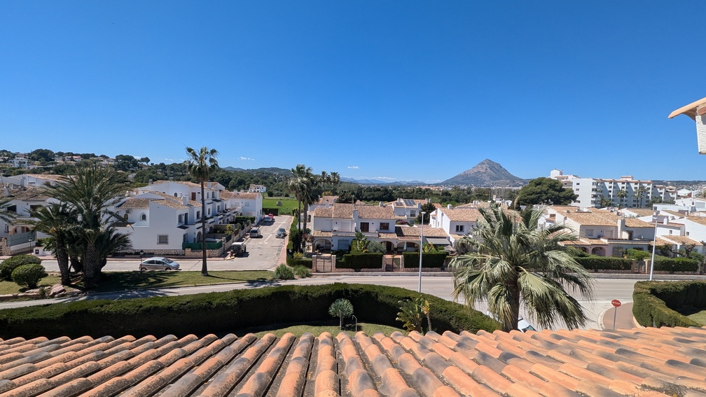 Verhoogd uitzicht vanaf het terras over de keramische dakpannen op de omliggende woonwijk van Jávea en de karakteristieke berg Montgó in de verte.