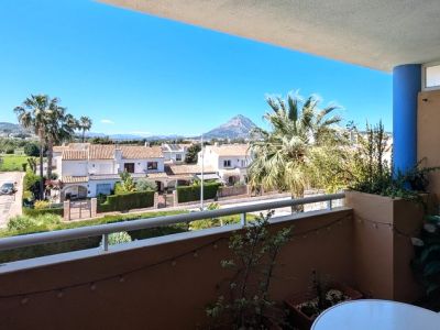 Open terras met witte balustrade en potplanten, met weids uitzicht over lokale woningen, groene gebieden en de opvallende Montgó berg onder een heldere hemel.
