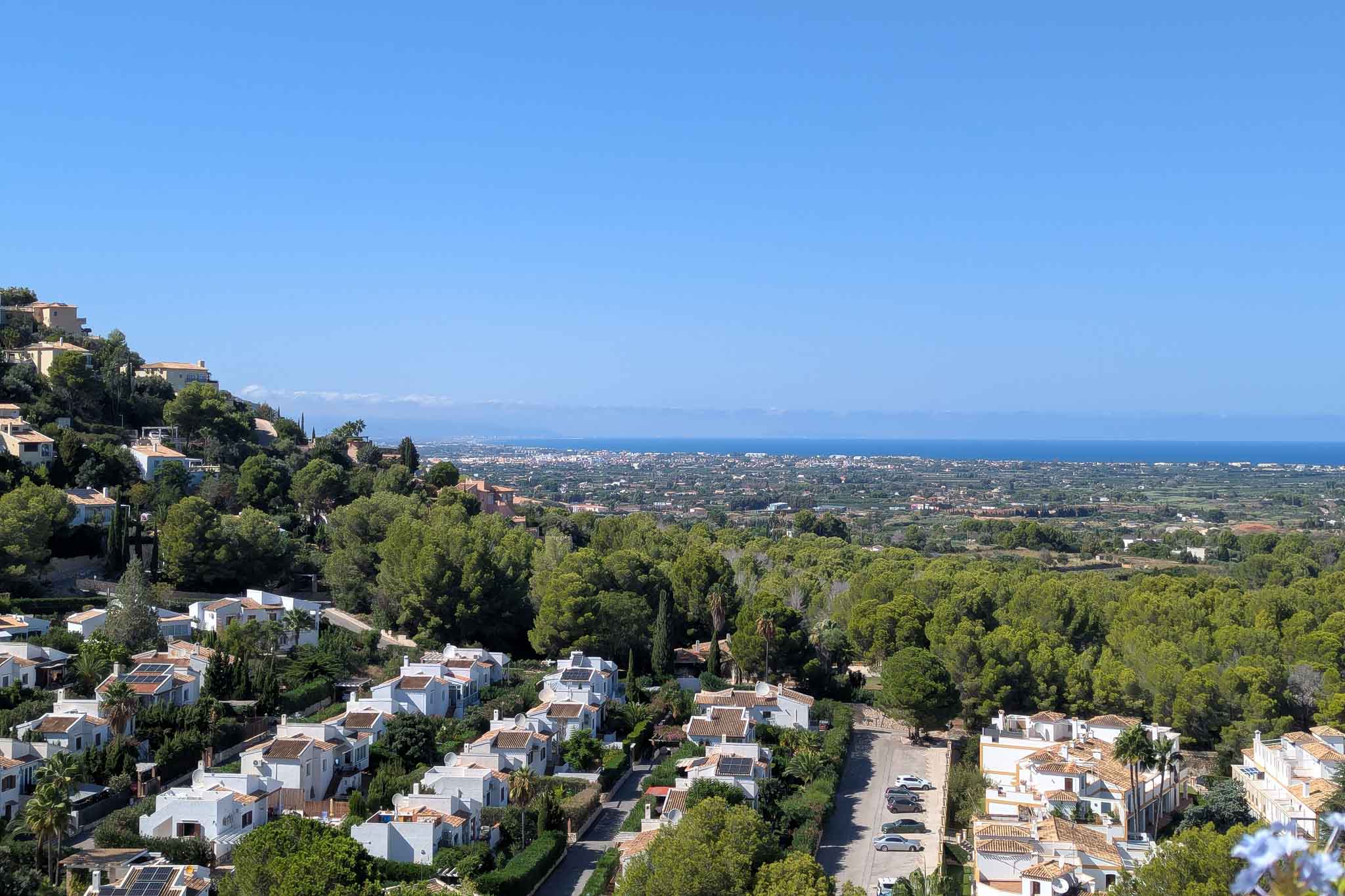 Panoramisch uitzicht vanaf La Sella over de kustlijn van Dénia, met witte woningen verscholen in de pijnboombossen en de Middellandse Zee aan de horizon.