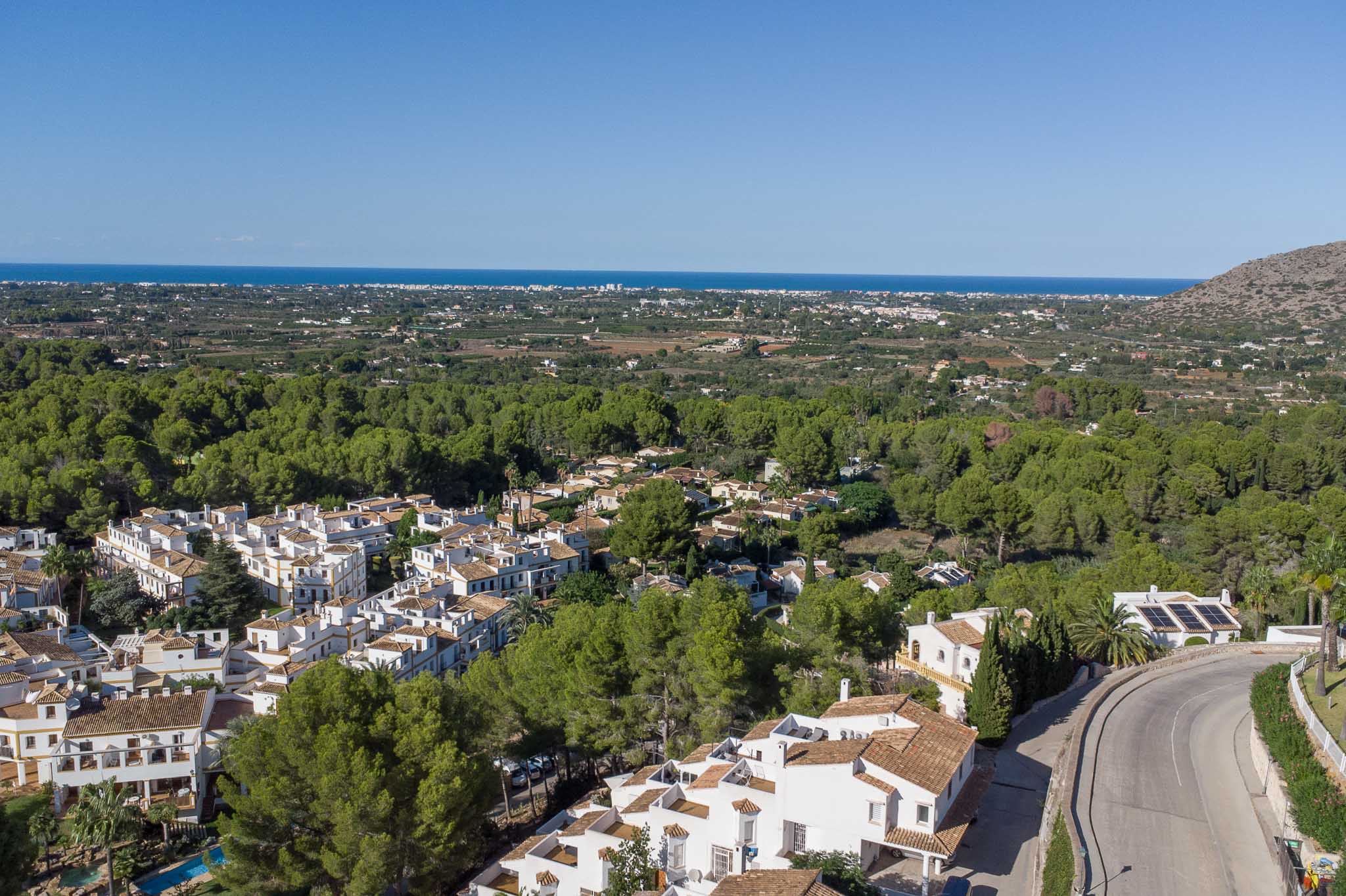 Verhoogd panoramisch uitzicht op het Las Mimosas complex in La Sella, omgeven door dennenbossen met de Middellandse Zee aan de horizon.