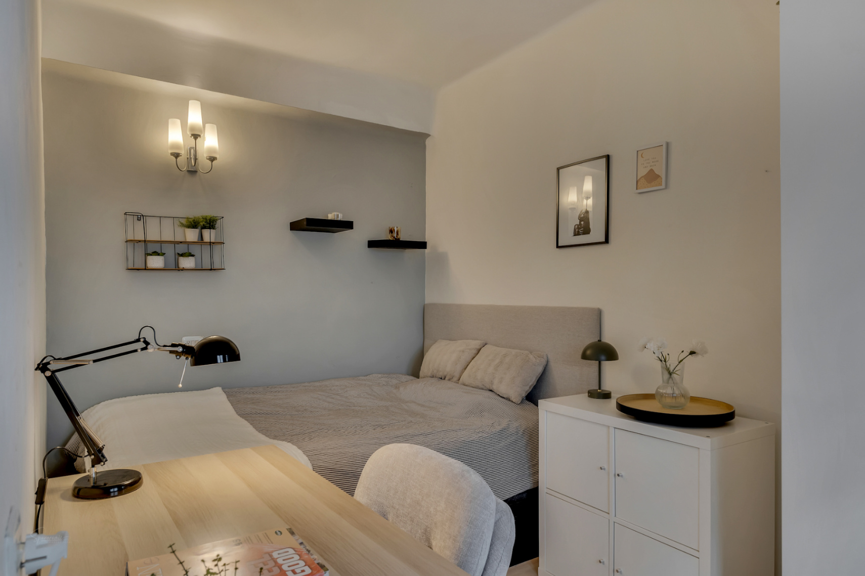 Lichte slaapkamer met een licht houten bureau en decoratieve wandplanken.