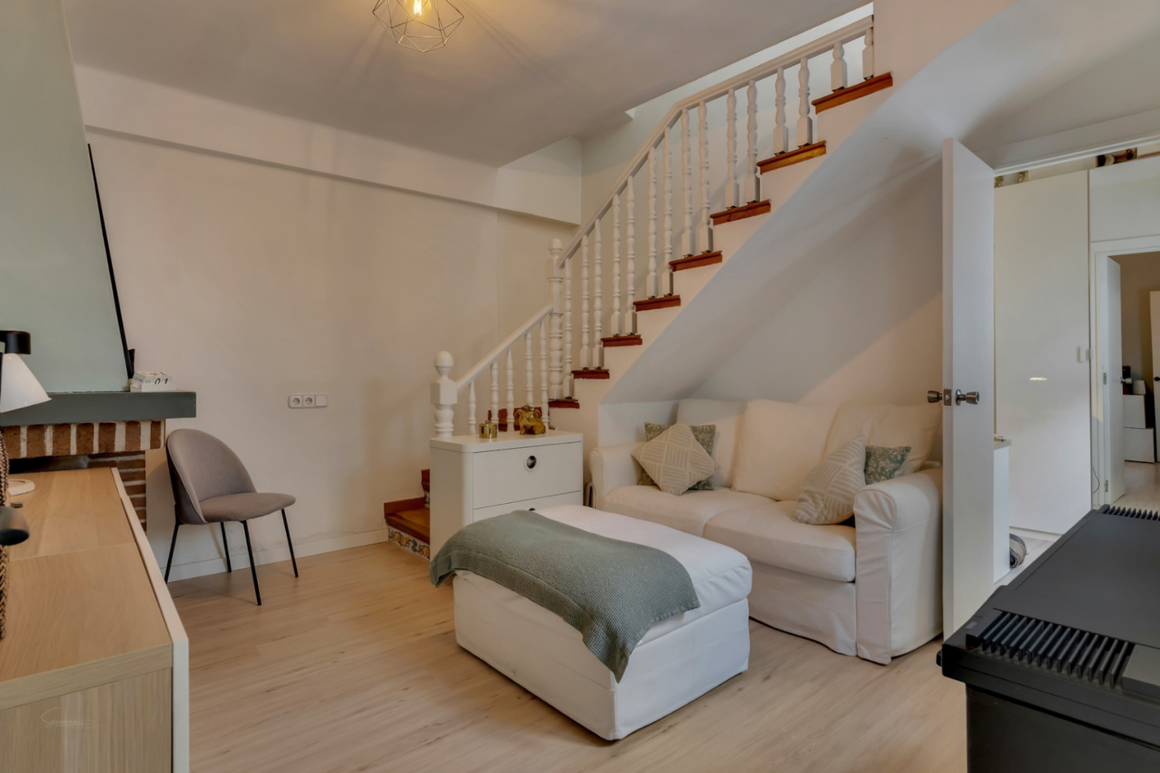 Lichte woonkamer met witte houten trap en lichte sofa. Minimalistisch, functioneel ontwerp.