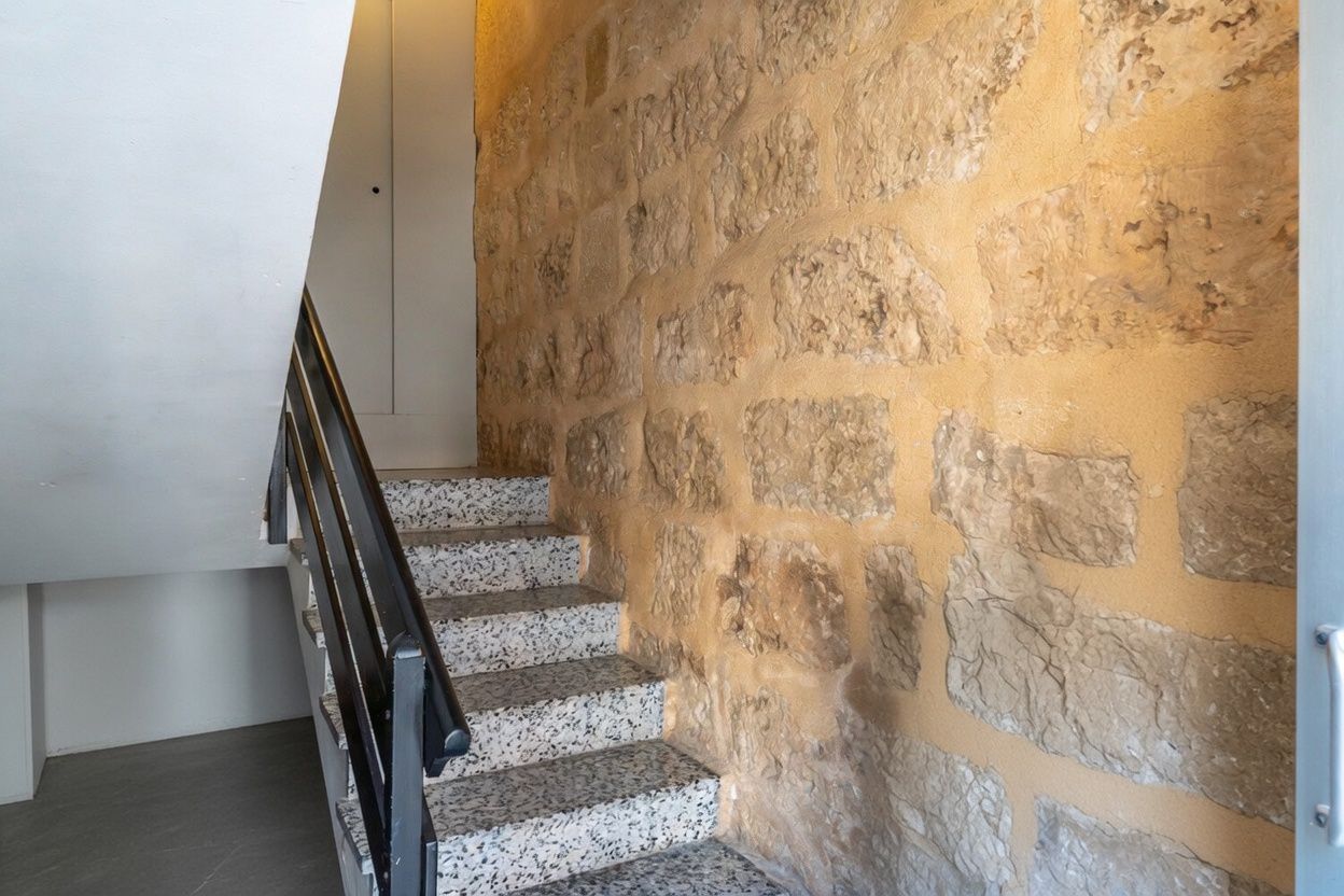 Trapdetail met een zichtbare stenen muur en terrazzotrappen.