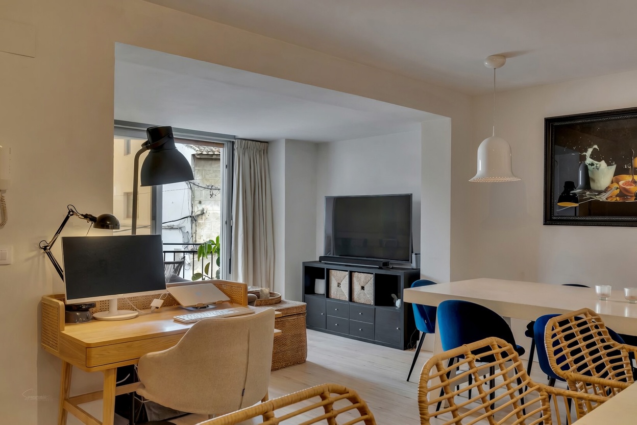 Uitzicht op de woon-eetkamer met licht houten bureau en toegang tot het balkon in Jávea.
