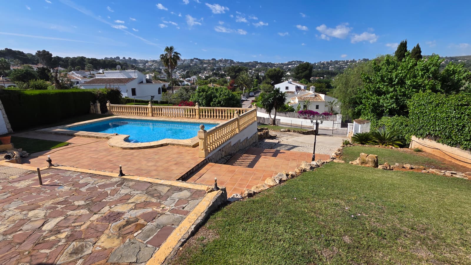 Buitenzwembad met klassieke balustrade, terracotta terras en weids uitzicht over de heuvels en villawijk van Jávea.