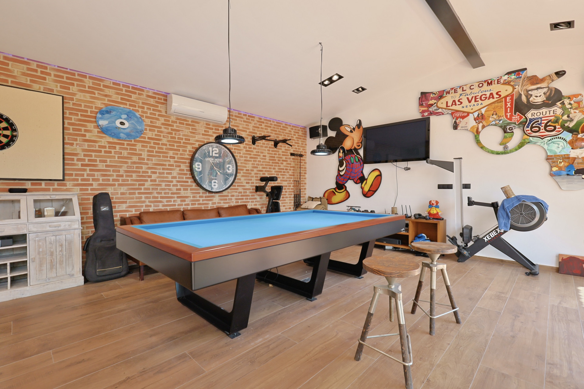 Speelkamer met blauwe biljarttafel, bakstenen muur en thematische decoraties.