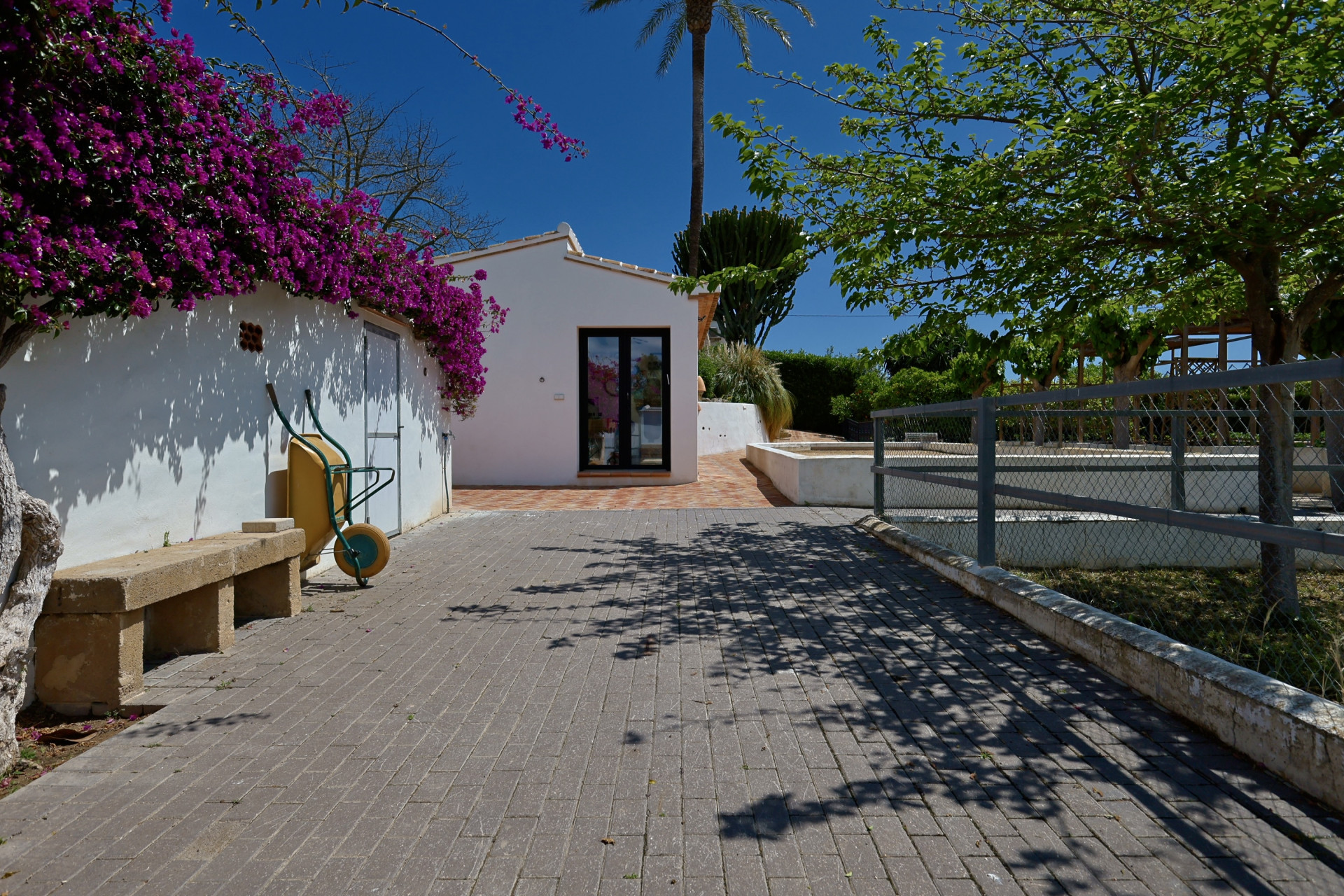 Villa-ingang met bougainville en stenen bank.