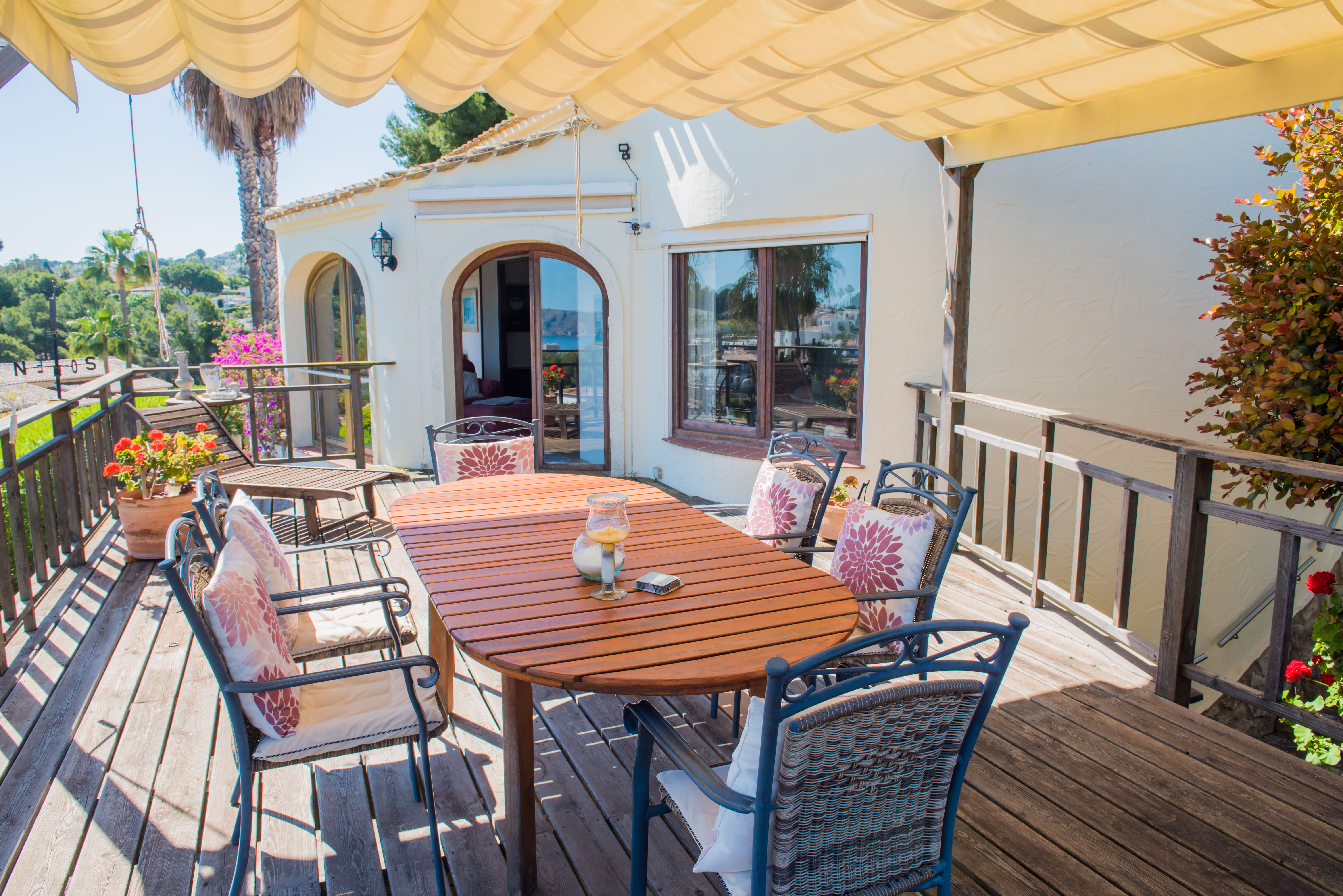 Overdekt terras met houten tafel en gestoffeerde stoelen, ideaal om te genieten van een panoramisch uitzicht op de Middellandse Zee.