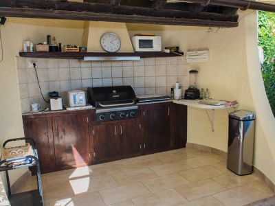 Buitenkeuken uitgerust met een grill, donkerhouten aanrecht en apparatuur.
