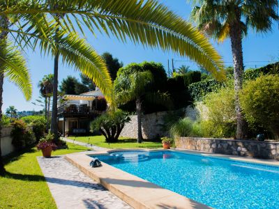 Uitzicht op het blauw betegelde zwembad en de mediterrane tuin met palmbomen in Jávea.