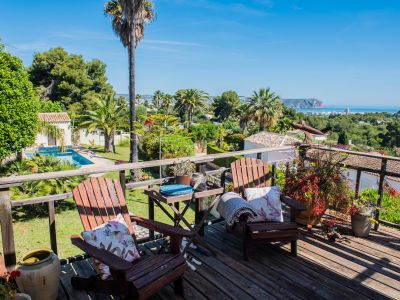 Uitzicht vanaf het houten terras met Adirondack-stoelen, tuinen en panoramisch uitzicht op zee in Jávea.