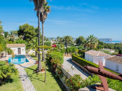 Verhoogd uitzicht op de mediterrane tuin met zwembad en roestige vliegtuigsculptuur in Jávea.