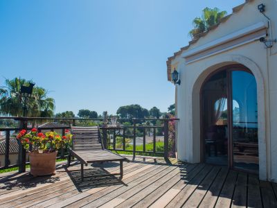 Zonnig terras met houten vloer, een ligstoel en uitzicht op het mediterrane landschap.