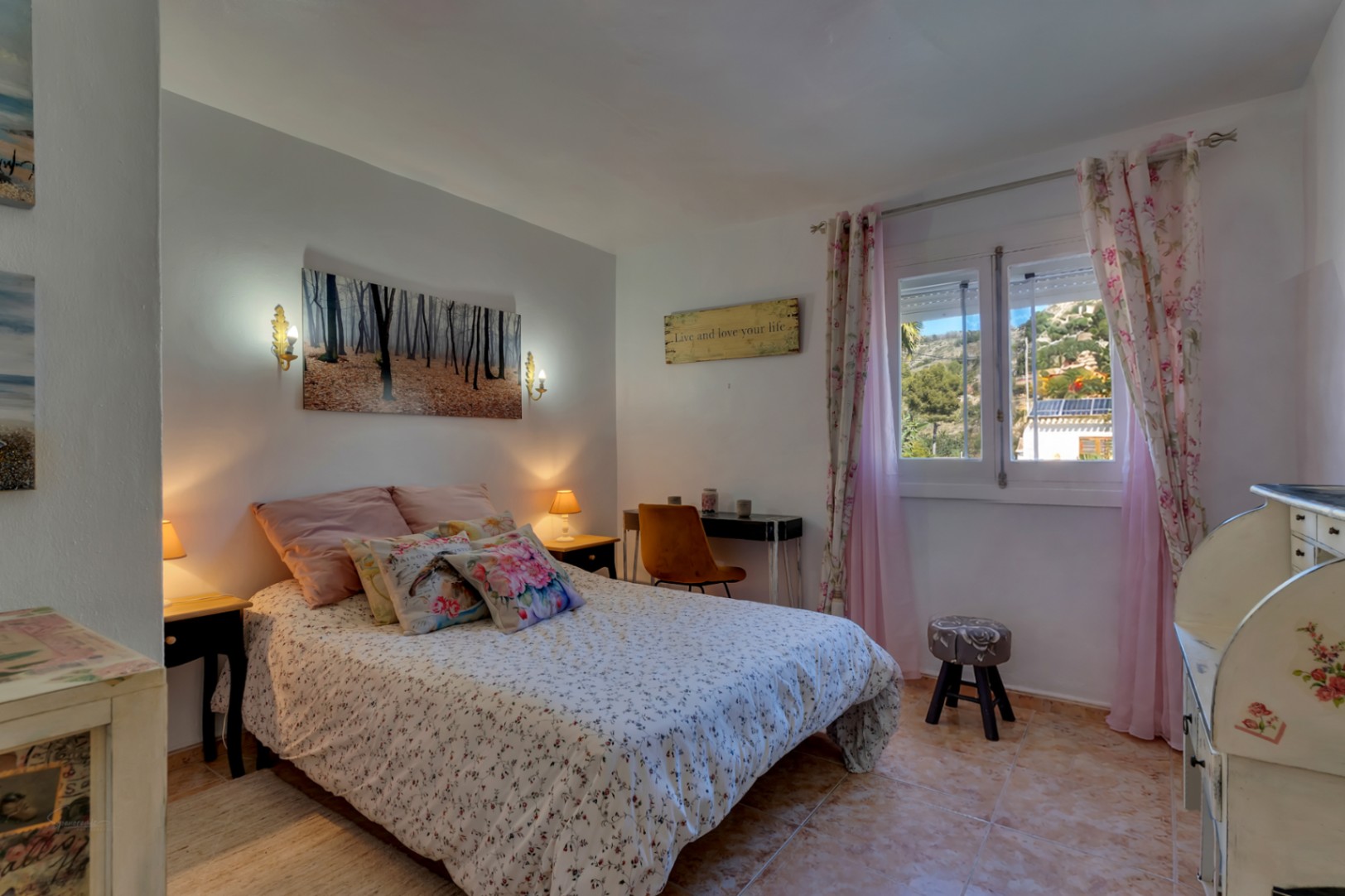 Lichte slaapkamer met tegelvloer, een functionele werkplek en een raam met uitzicht op de omliggende heuvels. Ingericht met klassiek meubilair en warme verlichting.