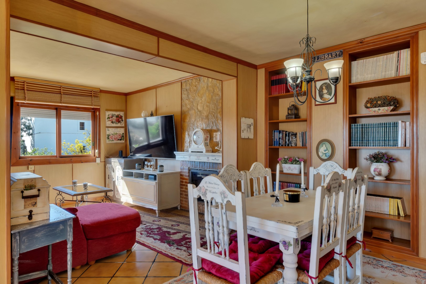 Woon-eetkamer met stenen open haard, houten wandpanelen en ingebouwde boekenkasten. Voorzien van rustiek meubilair en een traditionele tegelvloer.