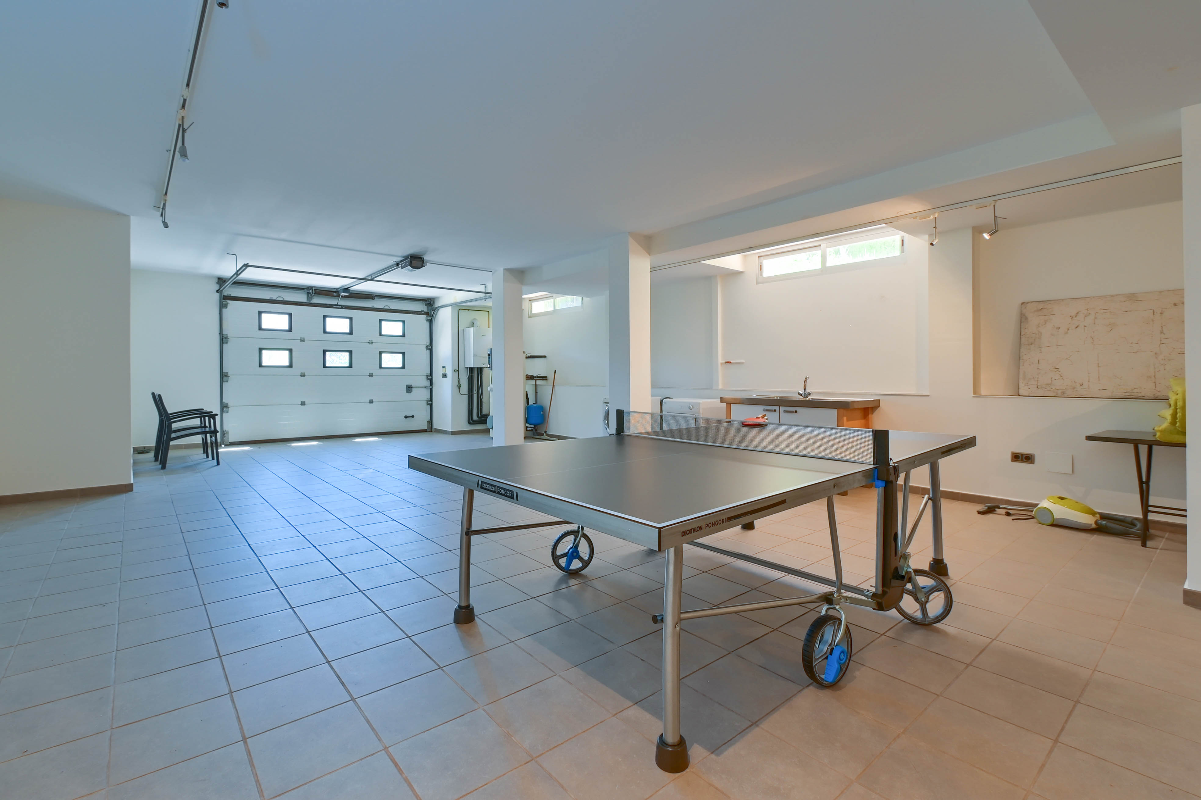 Recreatieruimte met Decathlon Pongori pingpongtafel, tegelvloer en toegang tot de garage.