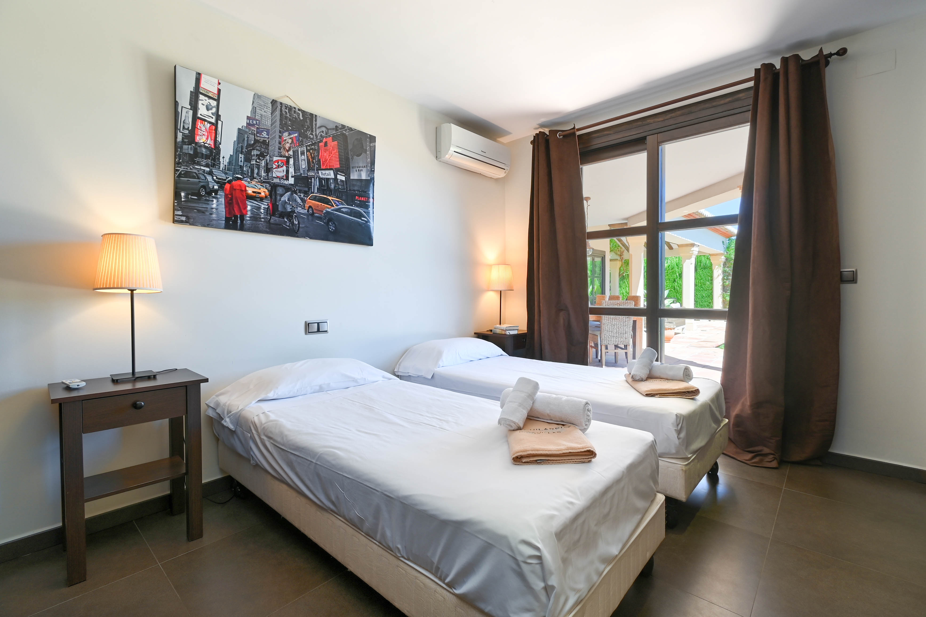 Slaapkamer met twee eenpersoonsbedden, wit bedlinnen en uitzicht naar buiten.