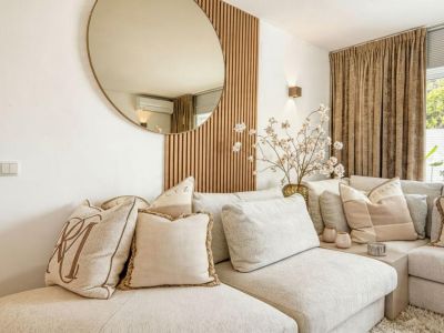 Detail van de woonkamer met een beige gestoffeerde modulaire bank en decoratieve houten wand.