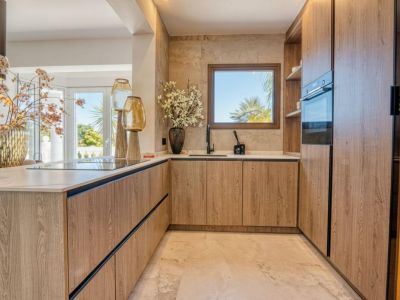 Keukendetail met lichte houten kasten en marmeren aanrechtblad, verlicht met natuurlijk licht.