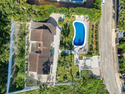 Luchtfoto van de villa met helderblauw zwembad, omgeven door tuinen en weelderig groen in Jávea.
