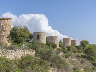 Uitzicht op historische stenen windmolens in Jávea, geïntegreerd in het mediterrane landschap.
