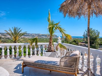 Zonnig terras met rotan ligbed en panoramisch uitzicht op Jávea.