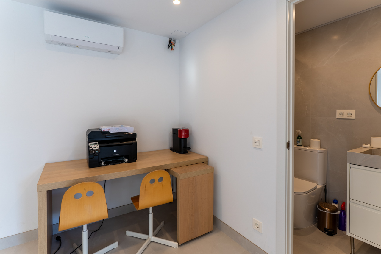 Functionele werkplek met licht houten bureau en toegang tot een ensuite badkamer.