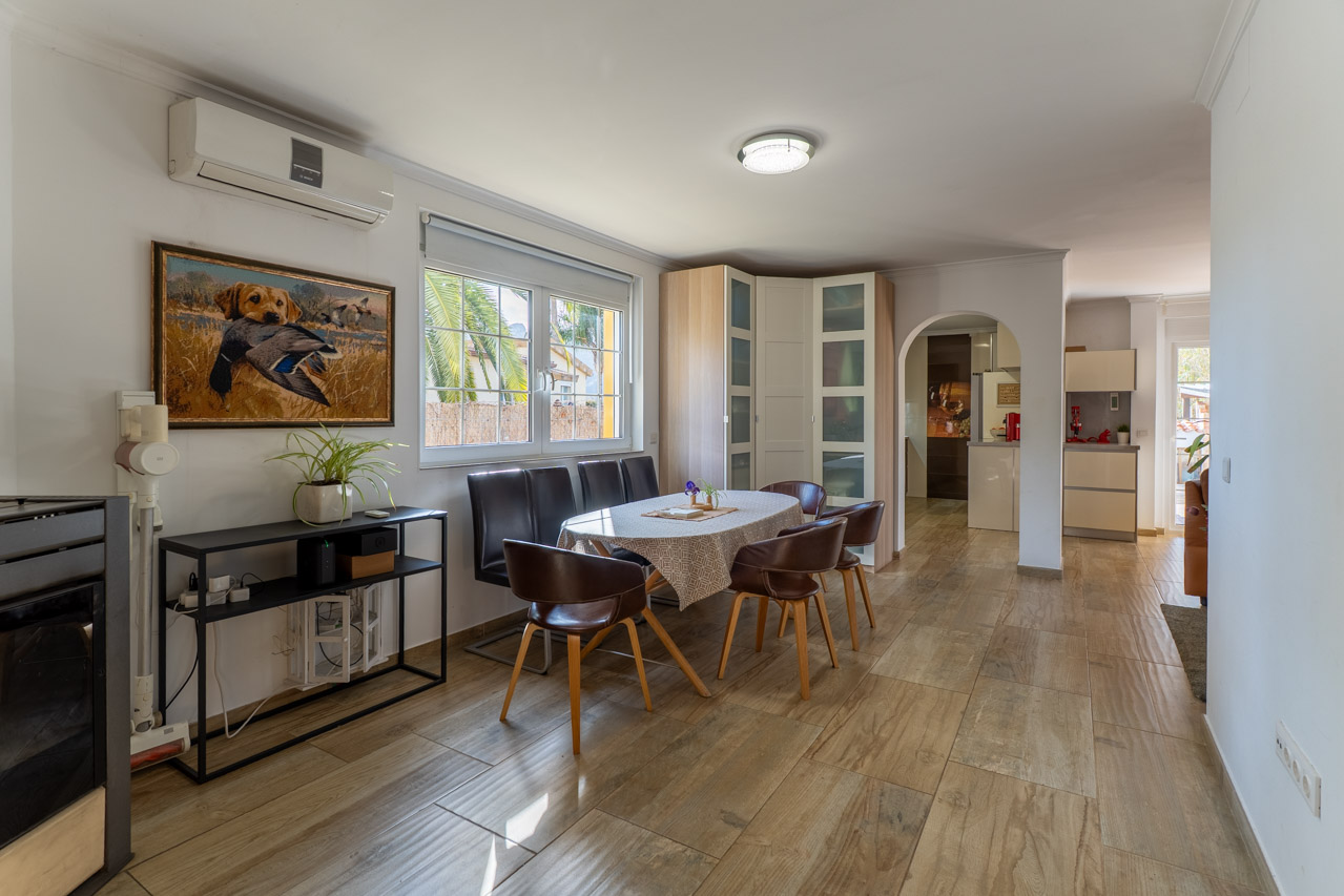 Lichte eetkamer met houtlook vloer, ovale tafel en zes bruine leren stoelen.