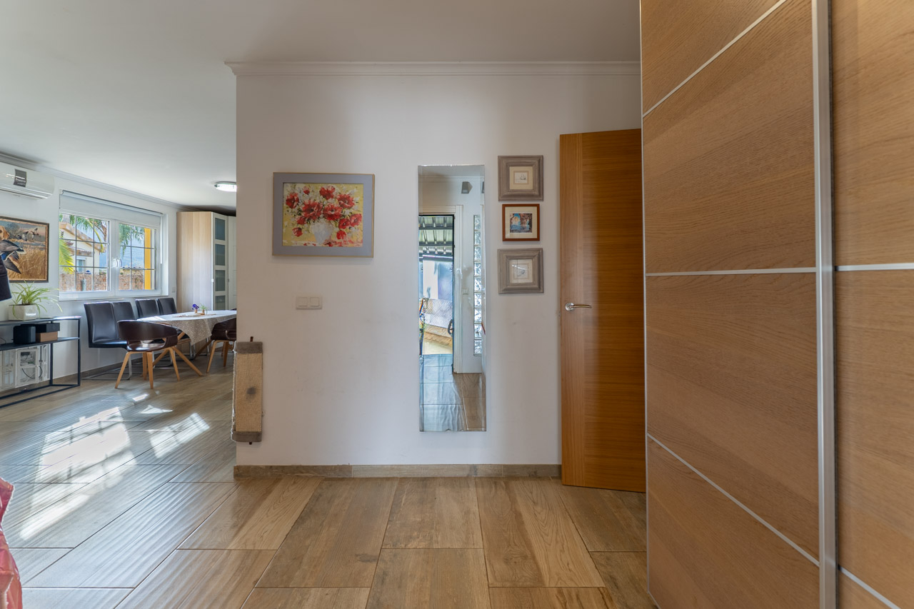 Lichte entree met keramische tegels in houtlook en wanddecoratie.